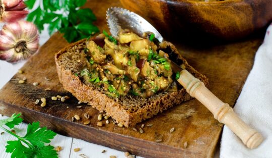 Salată de vinete cu usturoi și pătrunjel verde pe o felie de pâine și în bol