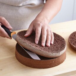 Femeie secționând blatul de tort în trei