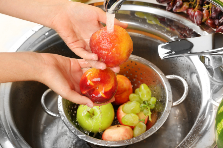 spălarea fructelor ilustrată cu ajutorul a două mâini care spală niște mere și struguri