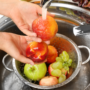 spălarea fructelor ilustrată cu ajutorul a două mâini care spală niște mere și struguri