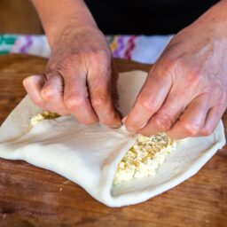 Femeie formând o plăcintă moldovenească cu brânză