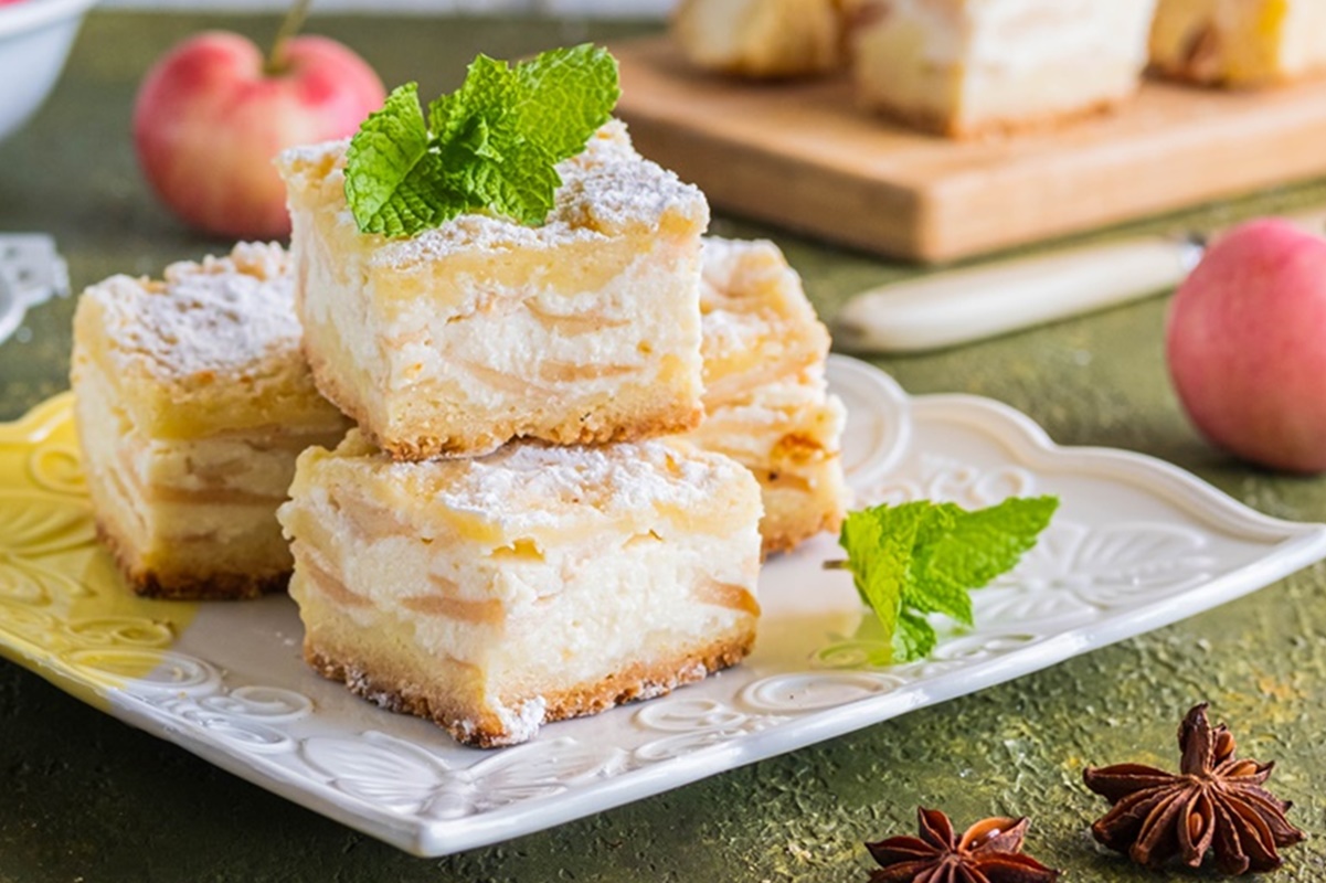 Porții de prăjitură cu mere și brânză pe o farfurie albă, dantelată