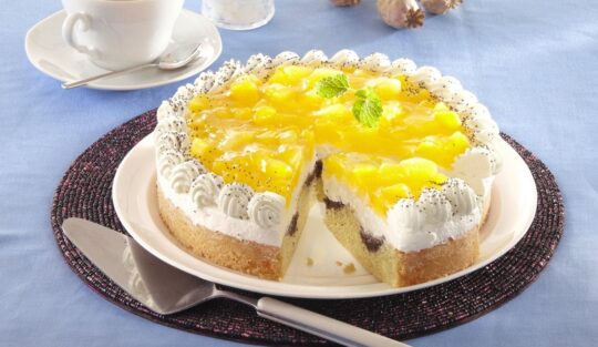 Tort cu compot de dovleac și blat marmorat cu mac porționat pe platou, alături de o spatulă de tort, o ceașcă cu cafea și tulpini de mac
