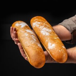 Bărbat ținând două pâini pe mâini