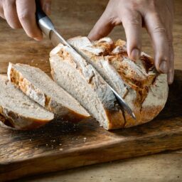 Persoană tăind pâine cu cartofi cu un cuțit