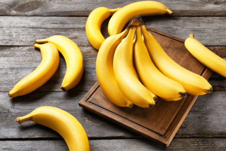 Cum se păstrează bananele ilustrat cu ajutorul mai multor banane pe un blat de lemn