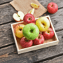 O lădiță plină cu mere pe o masă de lemn