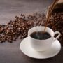 Cafea turnată într-o ceașcă, alături de boabe de cafea - Câte lingurițe de cafea se pun la o cană de apă. Raportul cafea – apă perfect, dezvăluit de o barista)