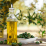 O sticlă cu ulei de măsline alături de o farfurie plină cu măsline negre