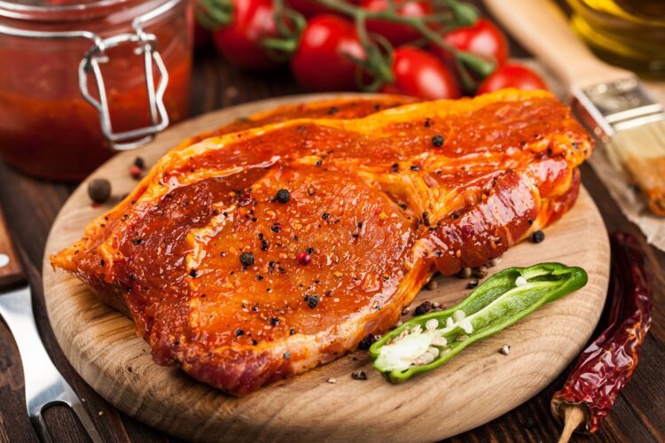 Exemplu de carne marinată pe un tocător de lemn, pentru a înțelege cum să marinezi carnea de porc pentru o friptură cu gust irezistibil