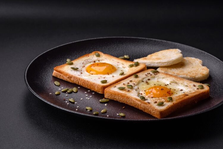 Ouă prăjite în pâine, decorate cu semințe într-o farfurie neagră