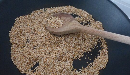 Semințe de susan amestecate în tigaie cu o spatulă