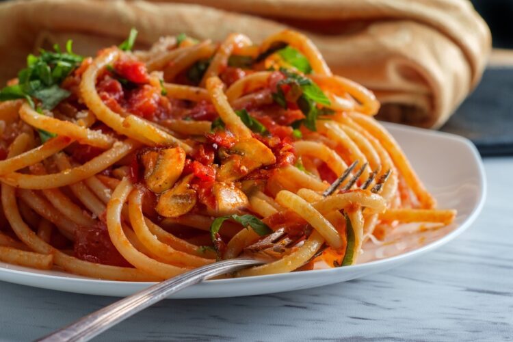 Porție de spaghete milaneze în farfurie cu furculiță