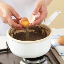 Femeie adăugând un ou în crema de mac
